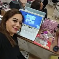 Raquel Aguilar Ramos trabajando con su portátil en su peluquería mientras prepara clases para sus alumnas