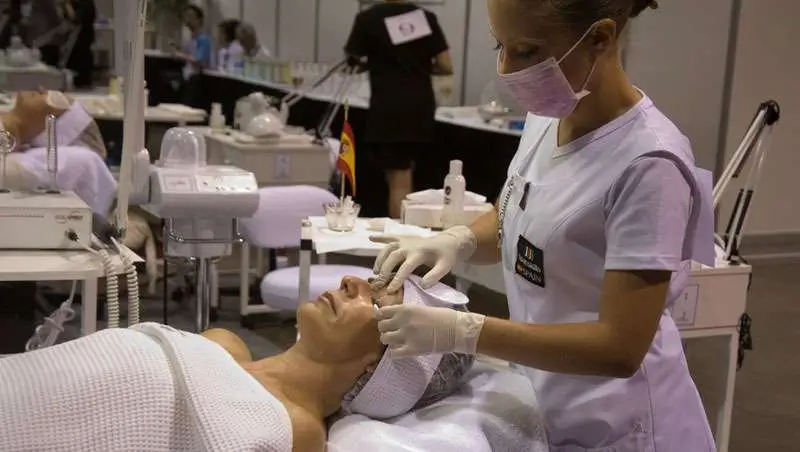 Aprender estética también implica práctica real Esteticista realizando tratamiento facial a una clienta durante una práctica de formación en estética profesional